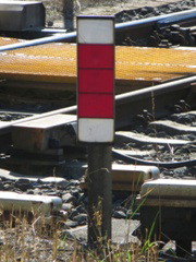 einzeln stehendes Mastschild, dazugehöriges Signal (|Asig|) hängt darüber an Signalbrücke